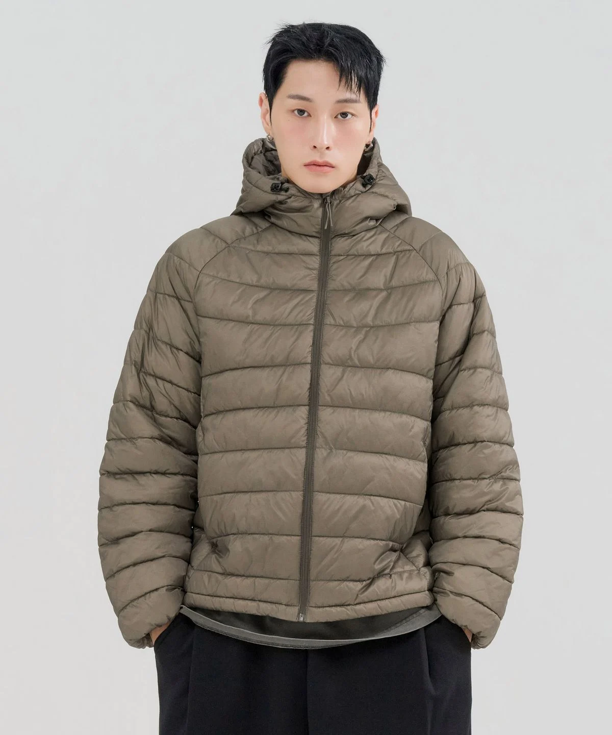 깔끔한 네이비 컬러의 체이스컬트 시어쉘 후드 패딩 점퍼가 침대 위에 가지런히 놓여 있는 모습