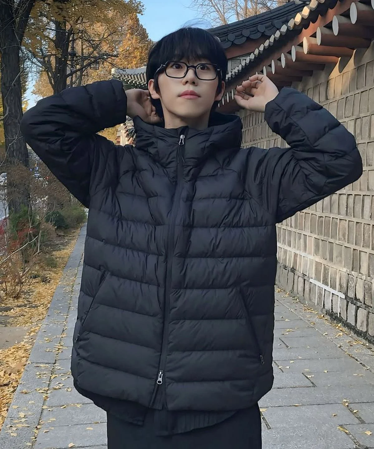 패딩의 2-way 지퍼를 위아래로 조절하며 스타일링하는 손길과 매트한 원단 질감 근접샷