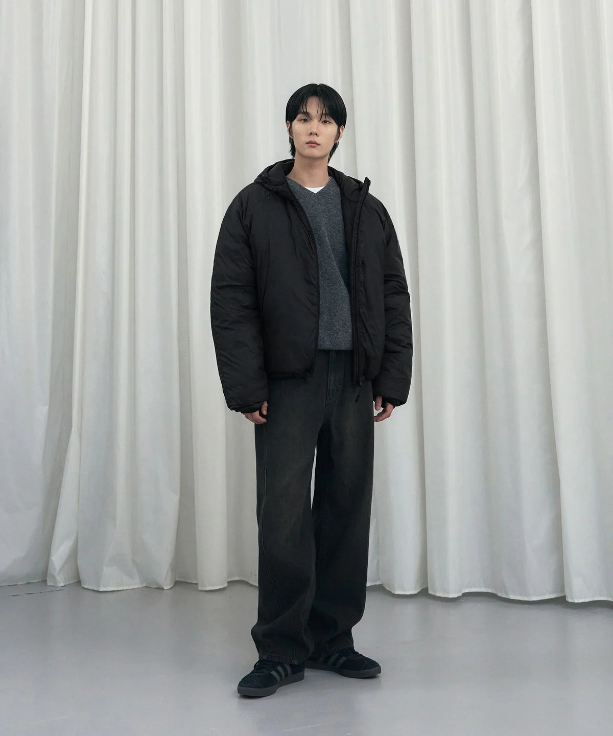 옷걸이에 정갈하게 걸려 있는 블랙 패딩의 전체적인 앞모습과 브랜드 로고 태그