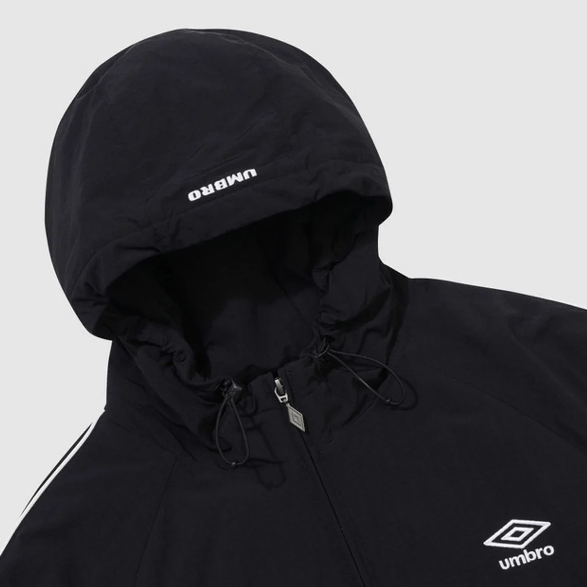 어두운 가을 저녁 가로등 아래에서 엄브로 아노락을 입고 있는 뒷모습과 로고 포인트가 돋보이는 사진